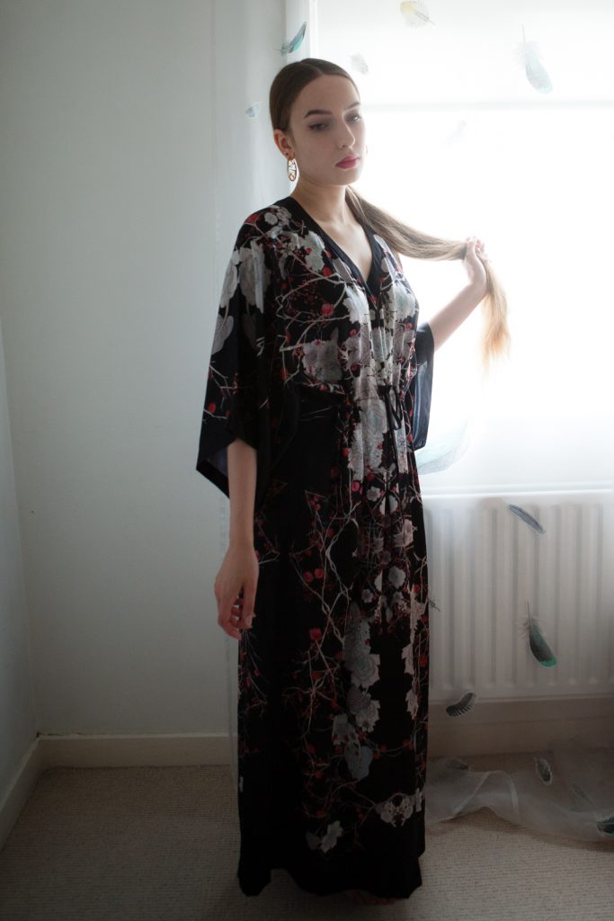 Model in silk lingerie. Black, silk, floor length caftan with flower pattern detailing by Meng.