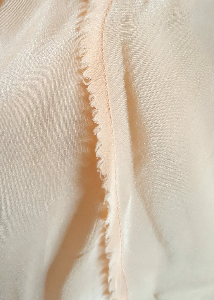 It is very rare to see a raw seam in contemporary lingerie, as it is time consuming and difficult to construct in a secure way. This 1930s teddy is sewn with raw seams that have been pinked (trimmed with zigzag toothed scissors to prevent fabric fraying) and finely topstitched (folded down and secured with an additional lockstitch, in this instance with a small stitch length). In contemporary manufacturing, it is much quicker to simply overlock this kind of seam. Photo by K Laskowska