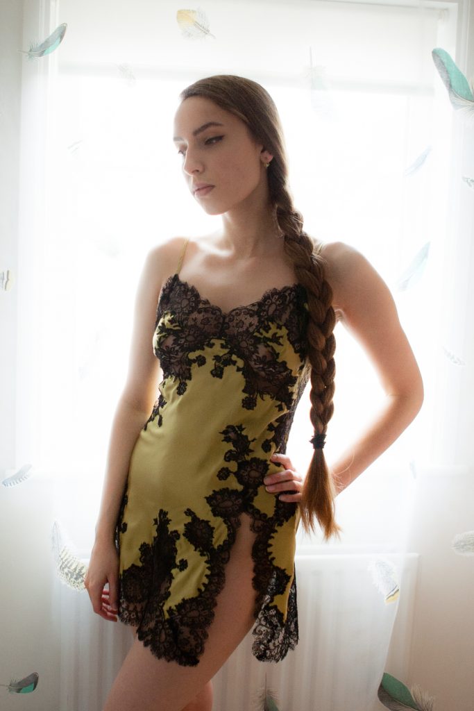 Model wearing Marjolaine yellow and black silk and lace slip with side seam slit.