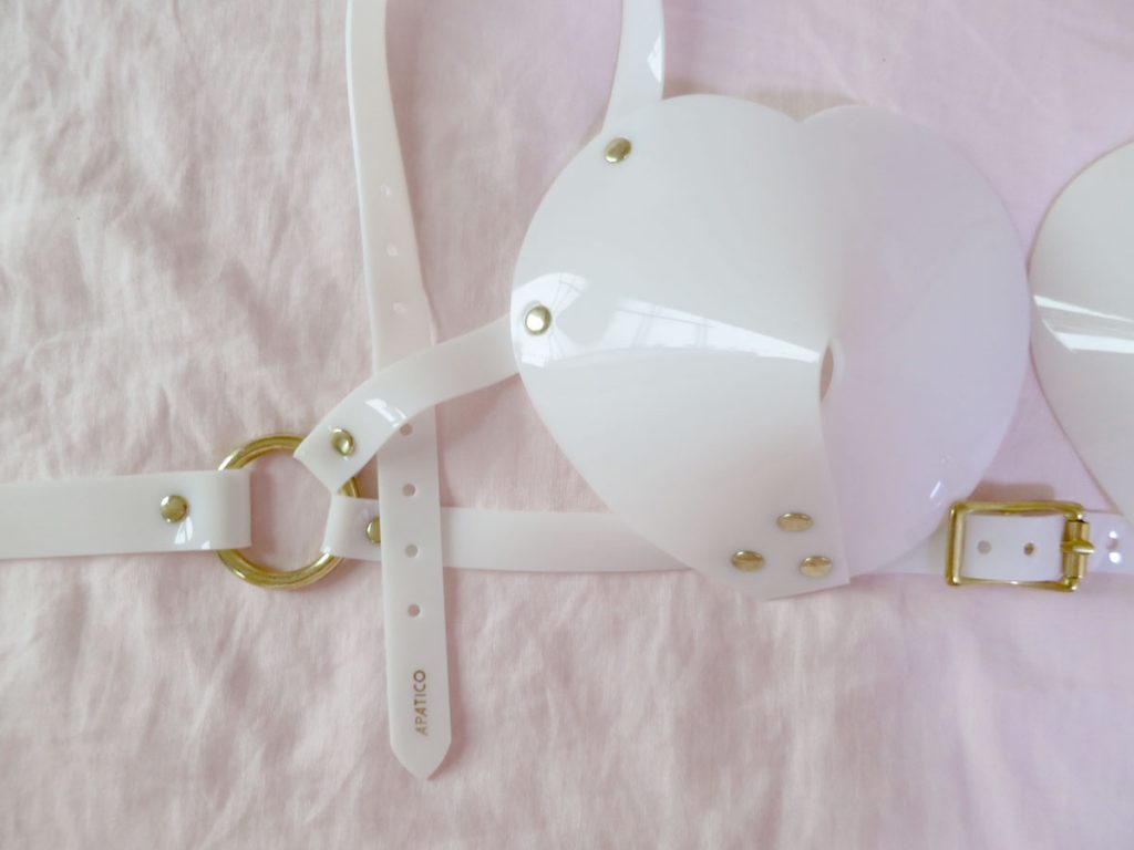 Close up of gold band stamp (reads: Apatico in gold) on Apatico white, PVC bullet bra halter strap.