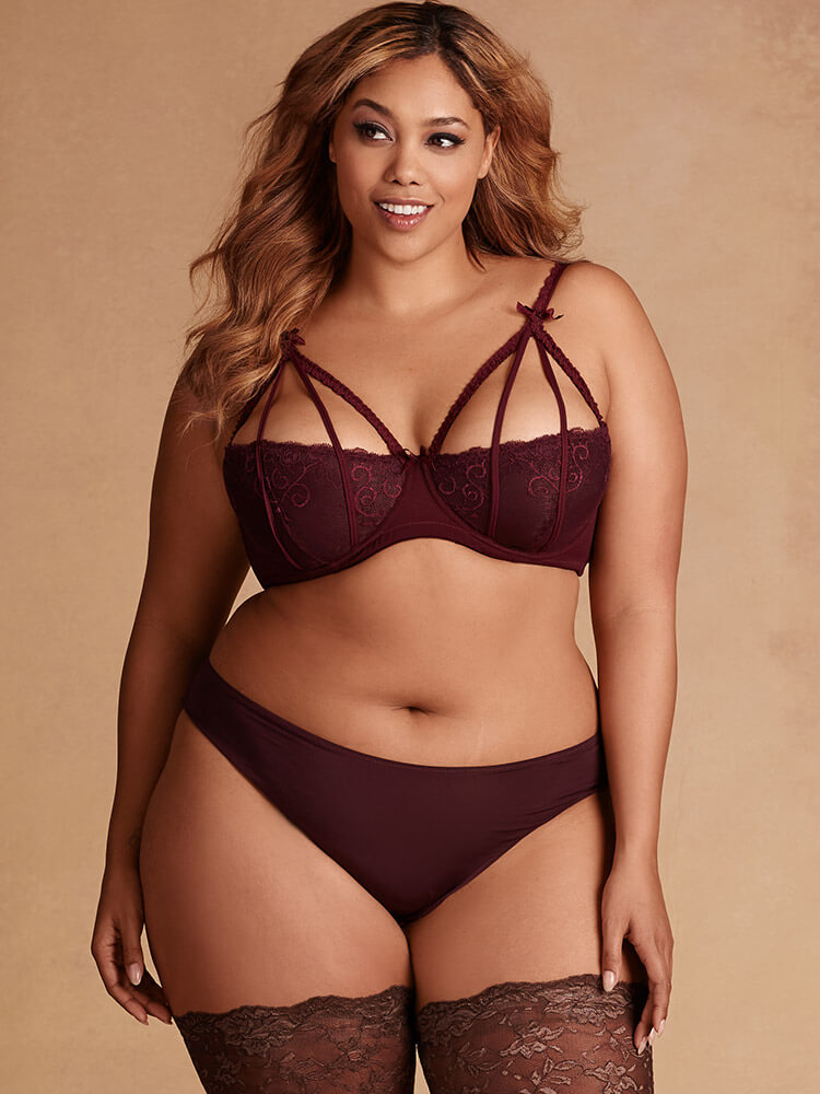 Hips & Curves. Lingerie Trends - Plus Size. Strappy burgundy/wine-colored bralette with plain briefs and brown thigh high stockings.